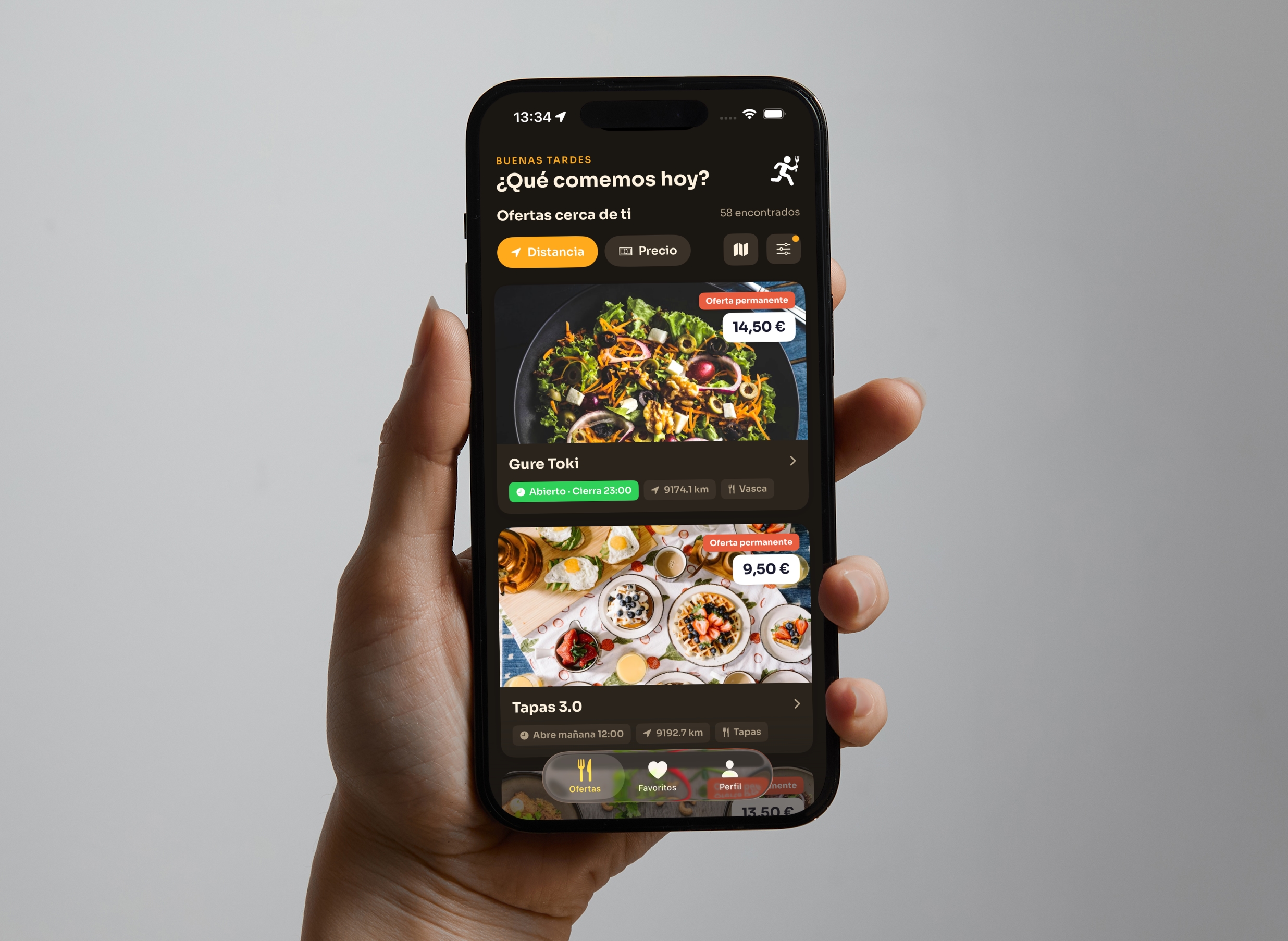 Mano sosteniendo un iPhone con la app Zampa mostrando ofertas cercanas